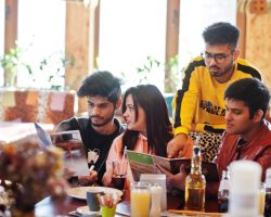 group-asian-friends-sitting-cafe-happy-indian-people-having-fun-together-sitting-couch-choose-meals-from-menu